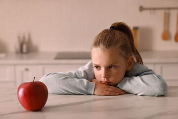 Canvas Print - Cute little girl refusing to eat apple in kitchen