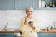 © Syda Productions - breakfast, food and people concept - happy smiling woman with spoon eating cereal on kitchen at home