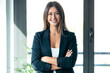 © nenetus - Beautiful young business woman standing while smiling looking at camera in the office.