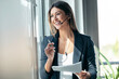 © nenetus - Elegant business woman talking with earphone while checking some documents in modern startup office.
