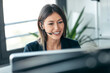 © nenetus - Attractive business woman making video call with computer while talking with earphone sitting in modern startup office.