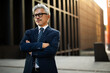 © Jelena - Portrait of senior businessman with crossed arms. Handsome man in suit outdoors.