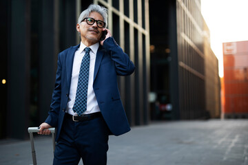 Wall Mural - Senior businessman outdoors. Middle-aged businessman talking to the phone.