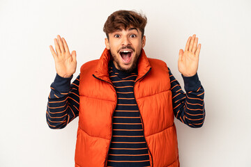 Young mixed race man isolated on grey background receiving a pleasant surprise, excited and raising hands.