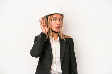 Poster - Young caucasian architect woman wearing a helmet isolated on white background trying to listening a gossip.