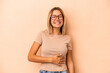 © Asier - Young caucasian woman isolated on beige background touches tummy, smiles gently, eating and satisfaction concept.