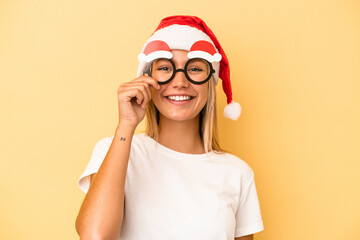 Poster - Young caucasian woman holding a christmas props isolated on yellow background