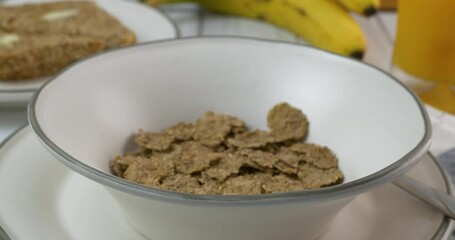 Poster - Pouring organic bran flakes into a bowl close up