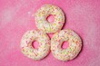 Three donuts on pink background.