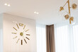 A huge clock in gold color on the wall in a modern beige interior. Interior Design. Soft selective focus, artistic noise.