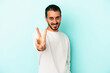 © Asier - Young caucasian man isolated on blue background joyful and carefree showing a peace symbol with fingers.