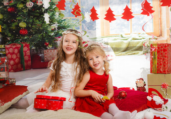 Wall Mural - Christmas or New Year Scene. Beautiful girls sisters in Christmas interior