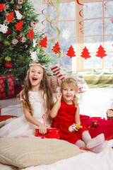 Wall Mural - Christmas or New Year Scene. Beautiful girls sisters in Christmas interior