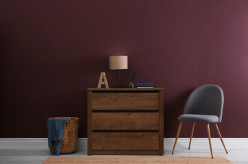 Elegant room interior with stylish chest of drawers, wicker basket and comfortable chair