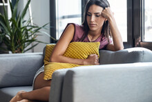 Shot Of Beautiful Young Woman Thinking And Worried Sitting On Couch At Home.
