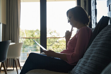 Sitting female examining a document inside a house