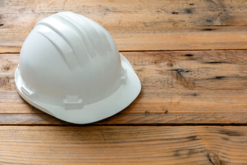 Wall Mural - Safety helmet, white color hard hat, construction site engineer protective gear wooden background