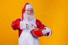 Santa Claus With A Bowl Beating Cake On Yellow Background