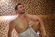 © zinkevych - A man in a towel sitting in sauna and having detox session