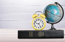 Retro Alarm Clock On The Old Holy Bible With Blurred World Globe