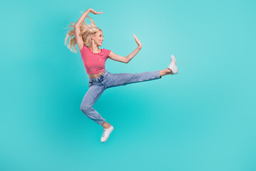 Photo of adorable pretty young woman dressed red t-shirt smiling jumping high practicing karate isolated teal color background
