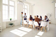 © Studio Romantic - Diverse business team having a meeting. Mixed race group of happy young people listening to presentation by their coworkers while sitting at a big office table in a spacious modern office interior