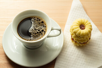 Xícara com café e dois biscoitos amanteigados.