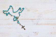 Rosary With Blue Beads On A White Wood Background With Copy Space