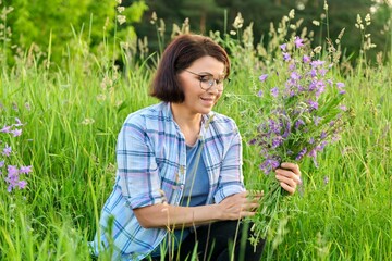 Wall Mural - Portrait of a middle-aged woman with a bouquet of wildflowers in nature