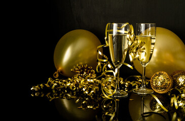 two glasses of champagne, golden balloons and decorations. new year's eve celebration composition.