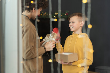 Sticker - Happy teenage boy in hoodie receiving bluetooth speaker in gift from mother on Christmas