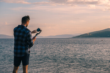 The use of technology. A male videographer shoots nature using a smartphone on a steadicam.