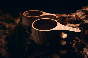 Tea in a two wooden national mugs Kuksa in the autumn forest at night