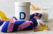 Vitamin d phial in scarf with autumn leaves, health and immunity concept
