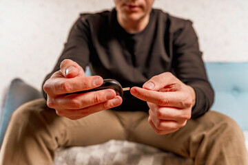 A man at home uses a glucose meter to measure blood glucose. Piercing a finger with a needle