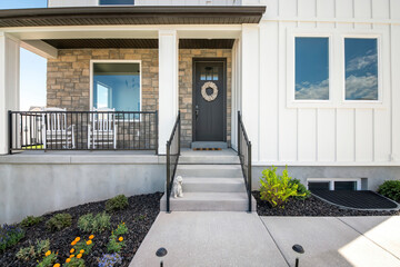 Facade of a house with stone veneer and white board and batten sidings