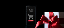 Online Shopping Gifts. Black Friday Banner With Internet Shopping App On Mobile Phone, White Gifts With Red Bow Falling On Black Background. Present Online Concept.