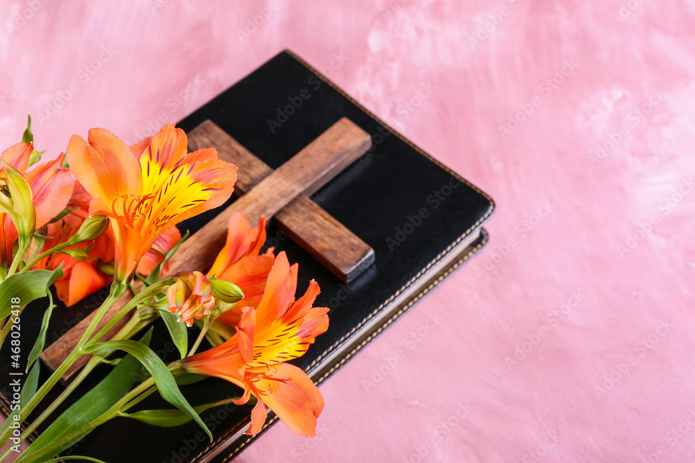 Holy Bible with cross and flowers on pink background