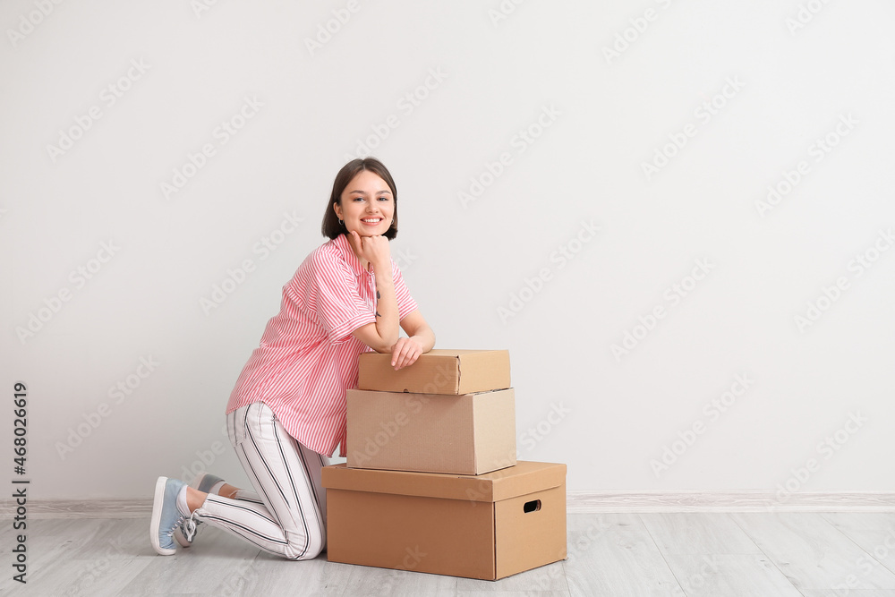 Young woman with wardrobe boxes near light wall