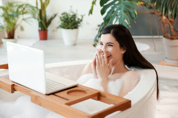 Poster - Pretty young woman watching video on laptop while taking bath at home