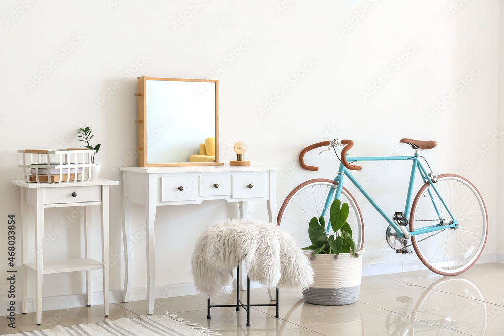 Interior of light room with dressing table and bicycle