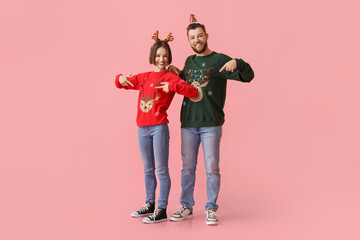 Wall Mural - Young couple in stylish Christmas clothes on color background