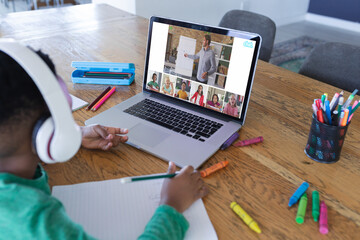 Wall Mural - African american boy using laptop for video call, with diverse elementary school pupils on screen