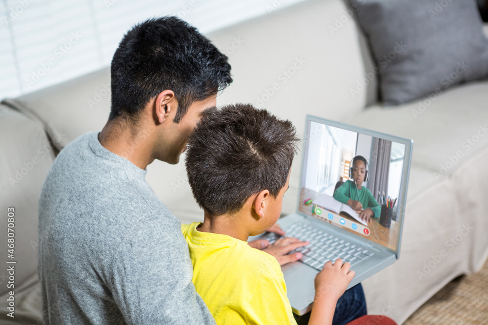 Biracial boy with father using laptop for video call, with elementary ...