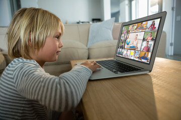 Canvas Print - Caucasian boy using laptop for video call, with smiling diverse elementary school pupils on screen