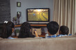 Rear view of family sitting at home together football match on tv