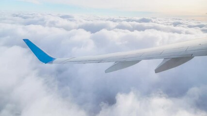 Wall Mural - Wing of an airplane flying above the clouds. Looks at the sky from the window of the plane, using airtransport to travel