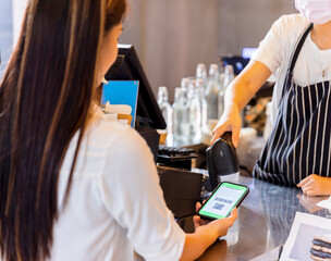 Technology and Payment concept. Young woman using wireless or contactless payment by smart phone.