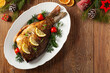 Fried carp whole. Served with lemon and cherry tomatoes on white plate. Christmas decoration. Top view.