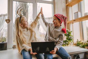 Boy and girl making video call using laptop at Christmas time